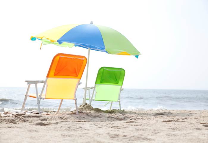 Narancssárga és zöld napozószékek a tengerparton egy színes napernyő alatt
